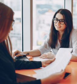 Two beautiful business women sitting in a office and engaged in the business
