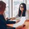 Two beautiful business women sitting in a office and engaged in the business