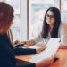 Two beautiful business women sitting in a office and engaged in the business